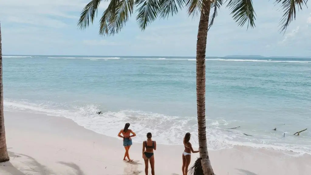Three women standing on the beach in our bikinis