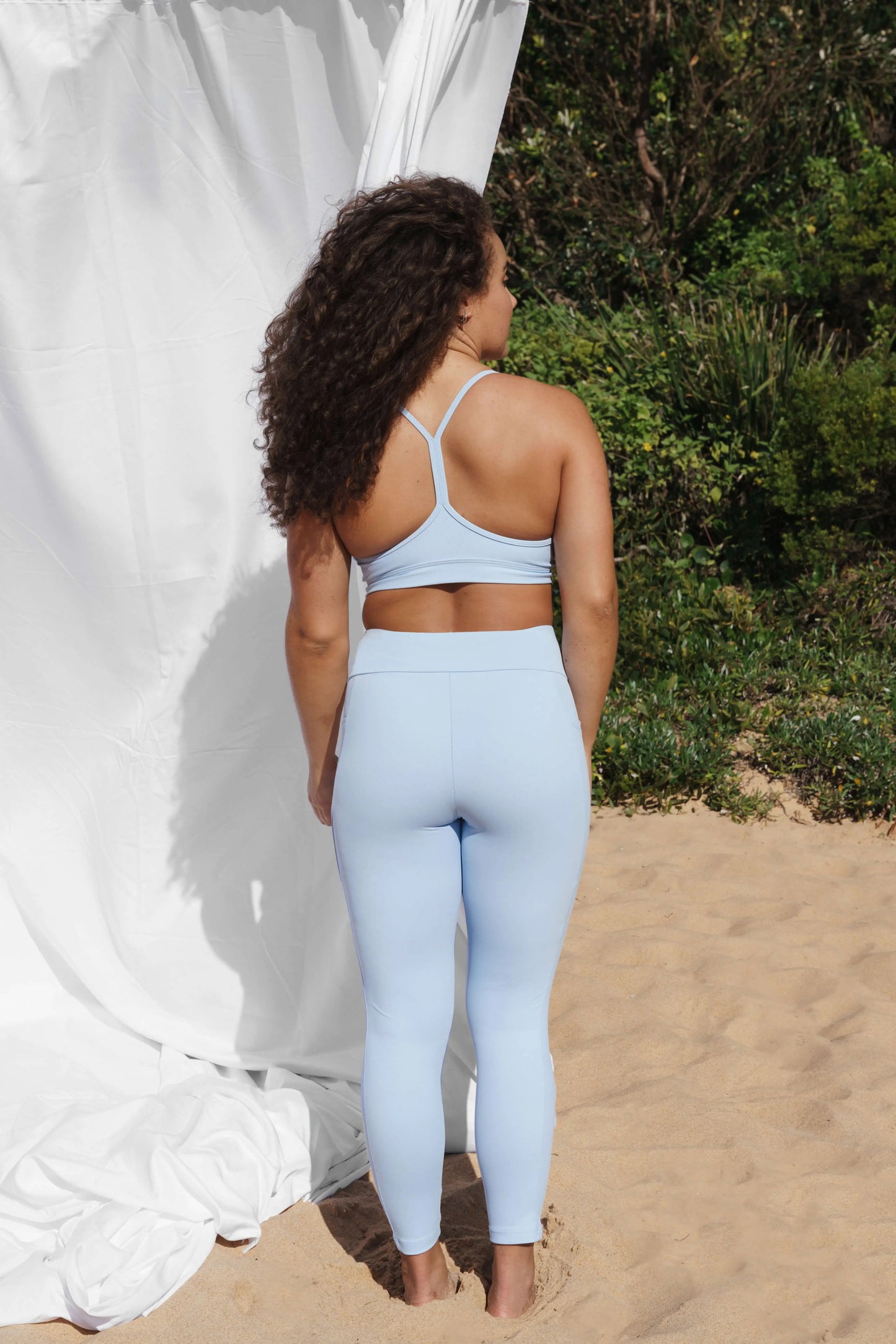 Our model at the beach, facing the back wearing a crystal Allawah legging and Inala crop top