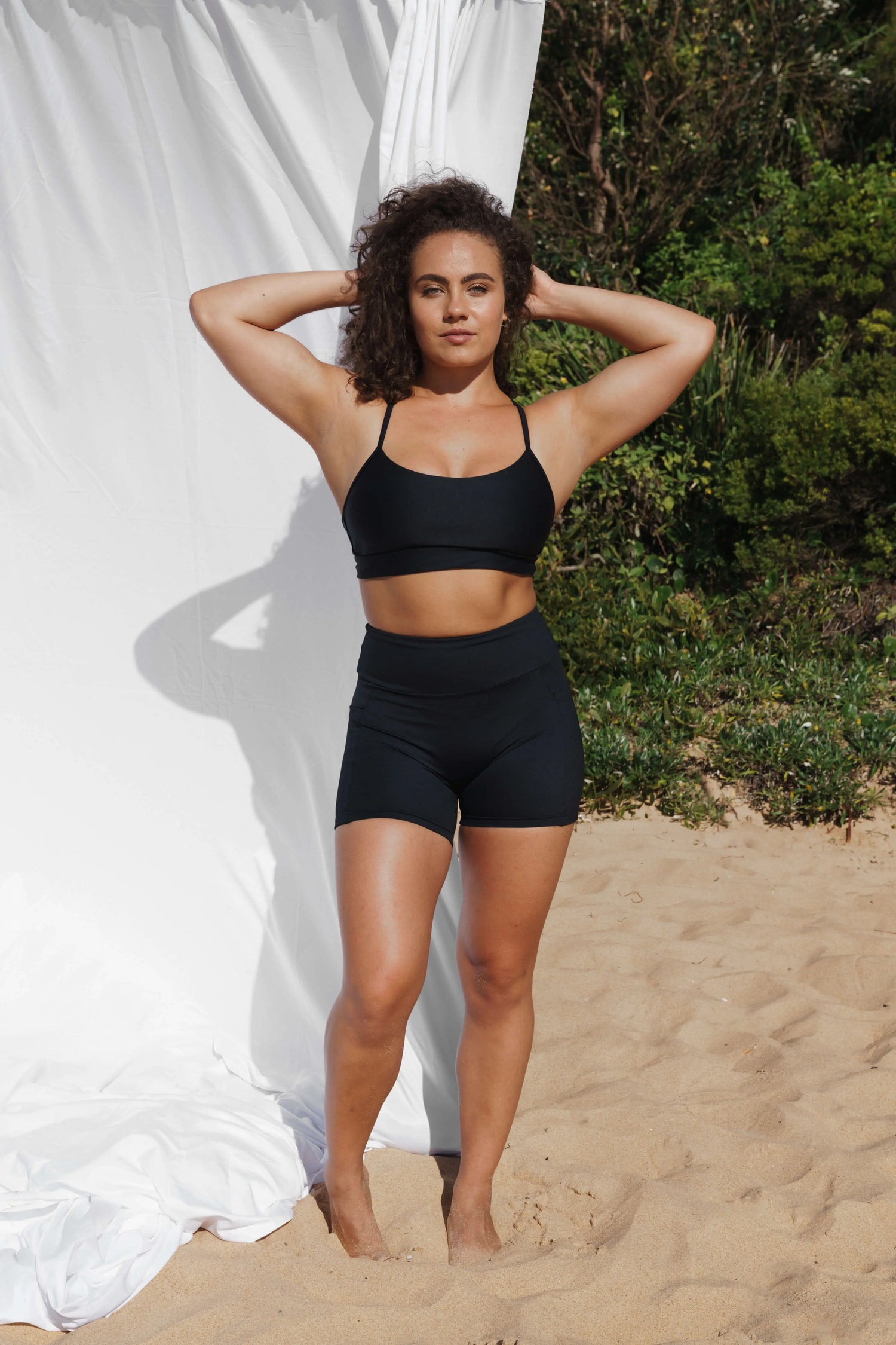 Model at the beach facing the front wearing our Inala Crop and Allawah Short in Black