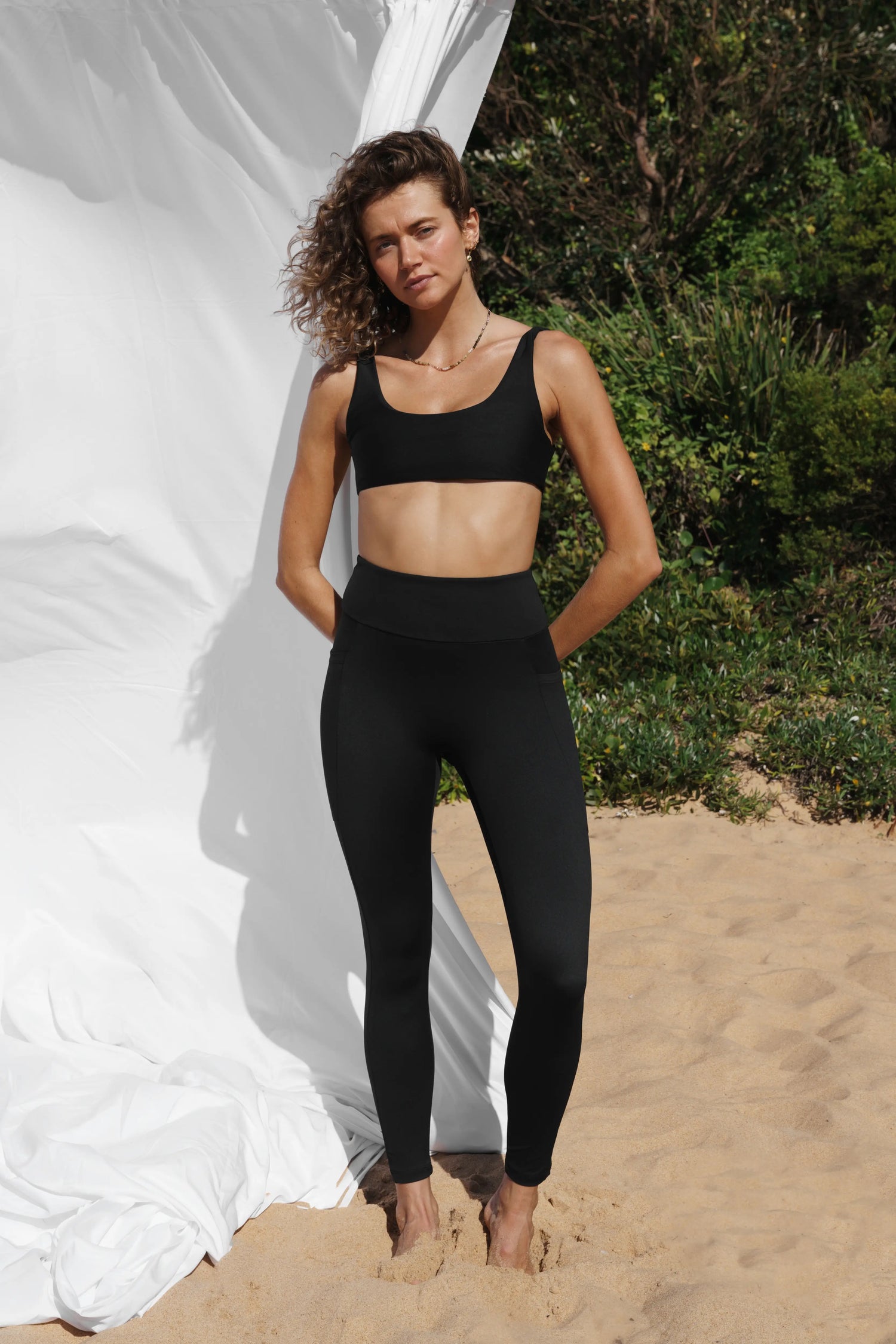 Our model at the beach, facing the front wearing a black Allawah legging and Lowanna Swim top